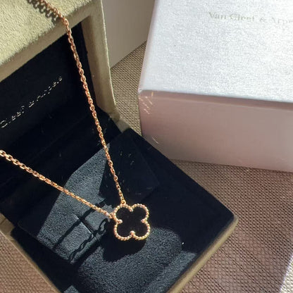 A Van Cleef & Arpels clover pendant necklace in rose gold, displayed inside its open signature green velvet jewelry box, with the brand's white box visible in the background.