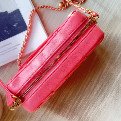 Pink handbag with gold zipper and chain on a wooden surface
