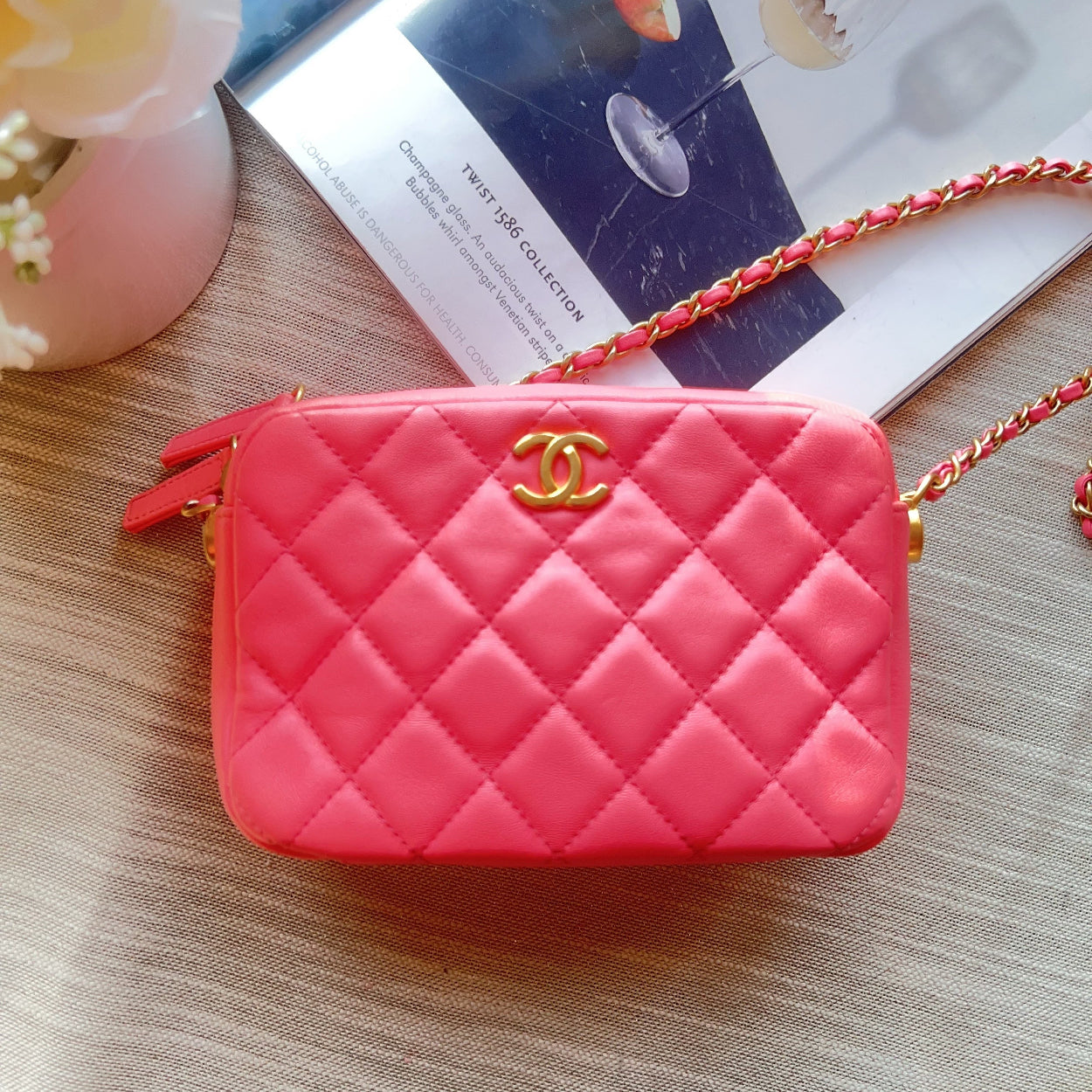 Pink quilted handbag with gold clasp on a wooden surface