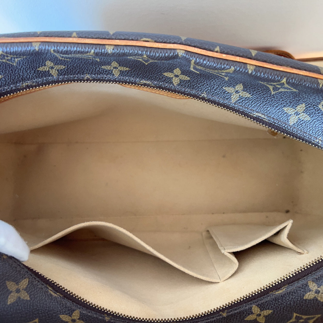 Close-up of a Louis Vuitton handbag with monogram pattern and beige interior.